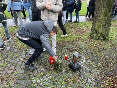 Ein Schüler stellt eine Kerze zum Gedenken auf das Mahnmal