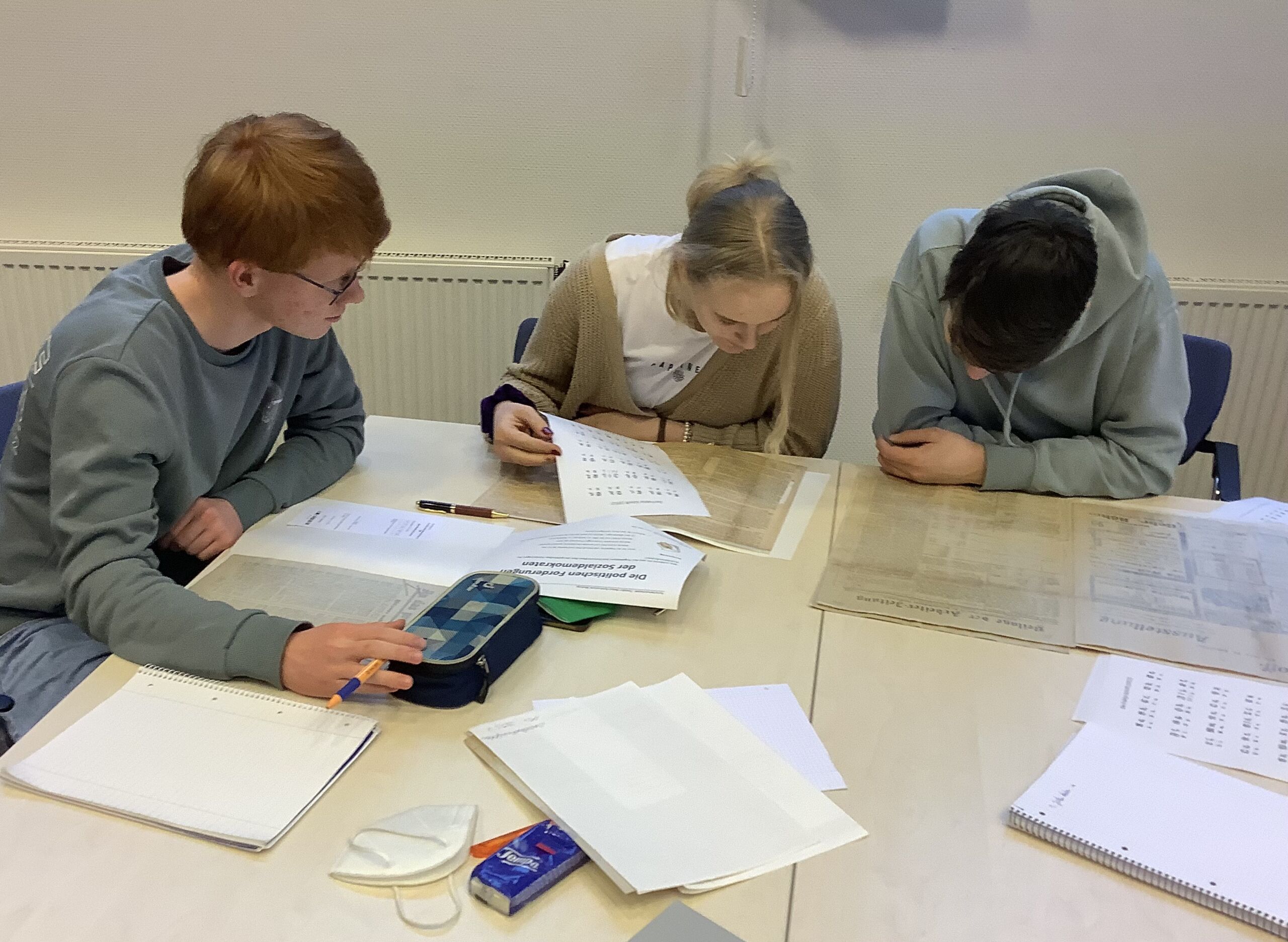 Schüler:innen arbeiten mit einer Zeitung aus dem Landesarchiv in Münster.